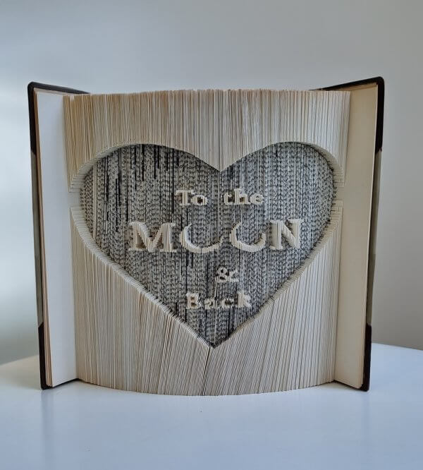 ספר מפוסל עם לב ובתוכו המשפט LOVE YOU TO THE MOON AND BACK - מתנה לאשה אומנות ישראלית מבית שאגא